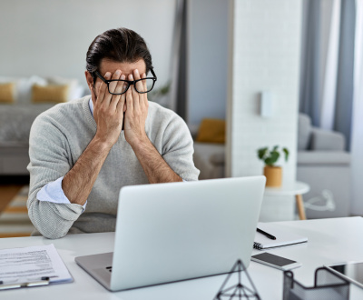 Tired male entrepreneur working on a computer at home. Frustrated man upset over his search engine rankings.