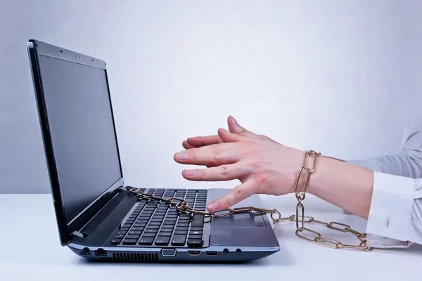A photo of a woman chained to he laptop.